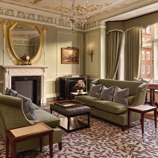 Classically inspired living room in Suite 205 at The Connaught, featuring pistachio green panelled walls, ornate cornicing, and period furnishings surrounding a marble fireplace.