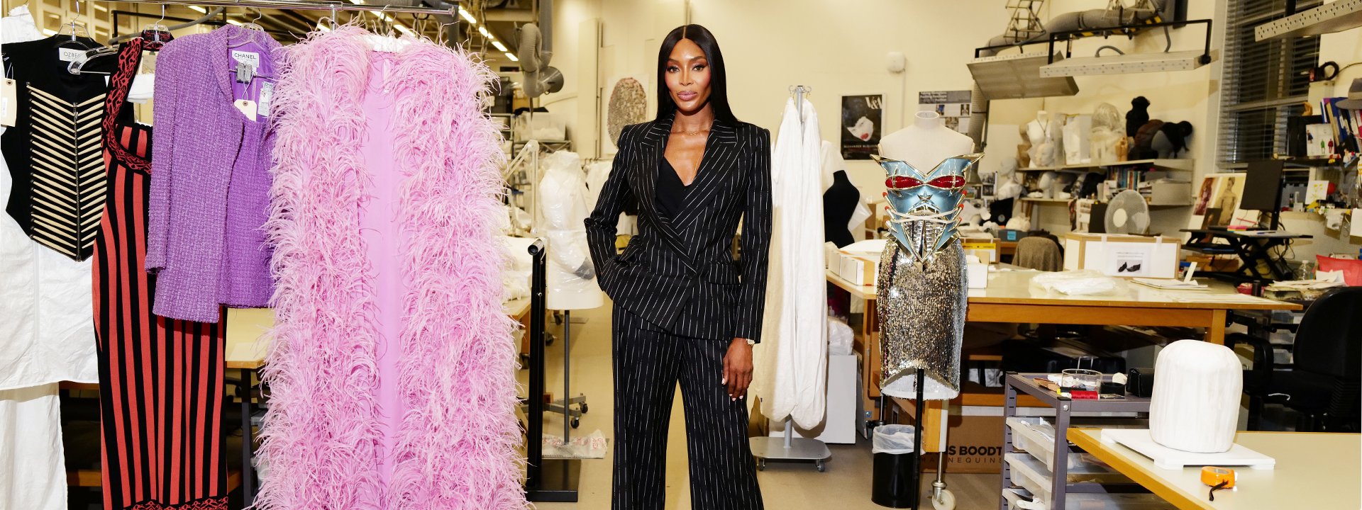 Naomi in pin striped suite in an atelier with clothes around her