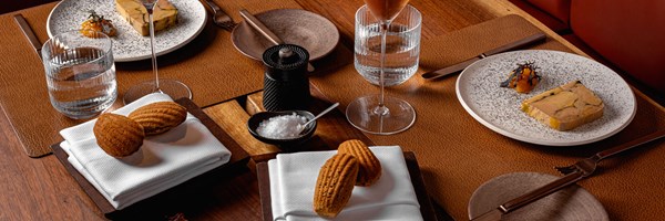 A sophisticated table setting featuring foie gras with accompaniments, artisan bread, and water glasses, creating a refined dining atmosphere.