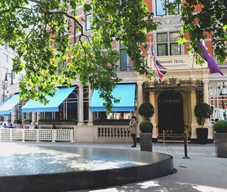 Exterior view of The Connaught hotel, with a doorman standing outside waiting for guests.