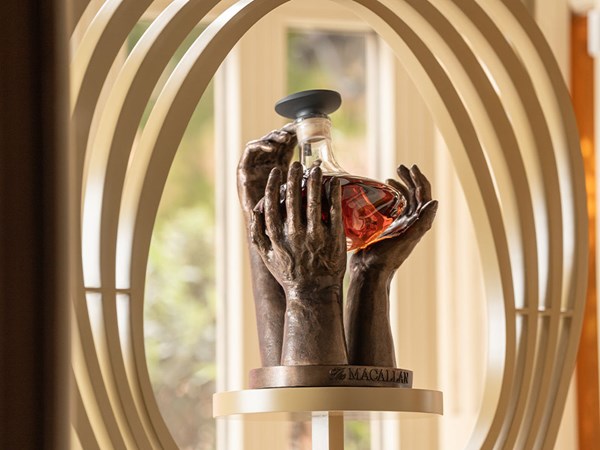 Three sculpture hands holding up a bottle of Macallan whisky