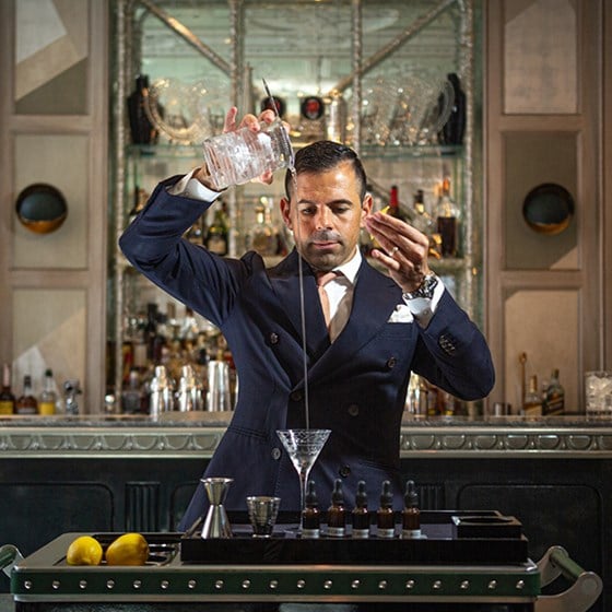 A focused mixologist in the process of making a delicious drink at The Connaught Bar.