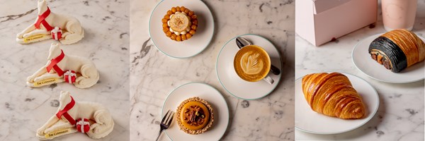 A delightful assortment of festive pastries, including white chocolate dogs with red ribbons, intricate tarts, a perfectly crafted latte, and a selection of golden croissants and viennoiseries, all displayed on a marble table for an elegant patisserie experience.