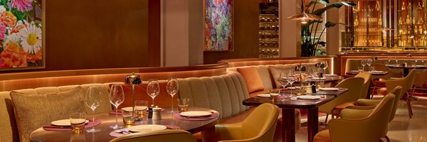 An elegant restaurant setting with warm lighting, cozy booths, and stylish décor featuring vibrant artwork.