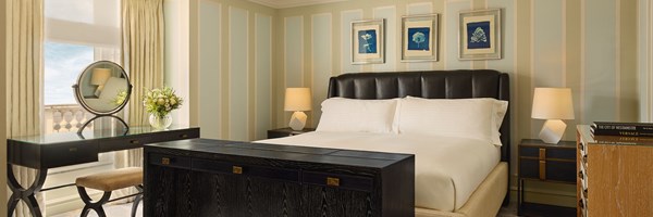 Sophisticated bedroom with a leather-upholstered headboard, striped walls, and a sleek black dressing table by the window